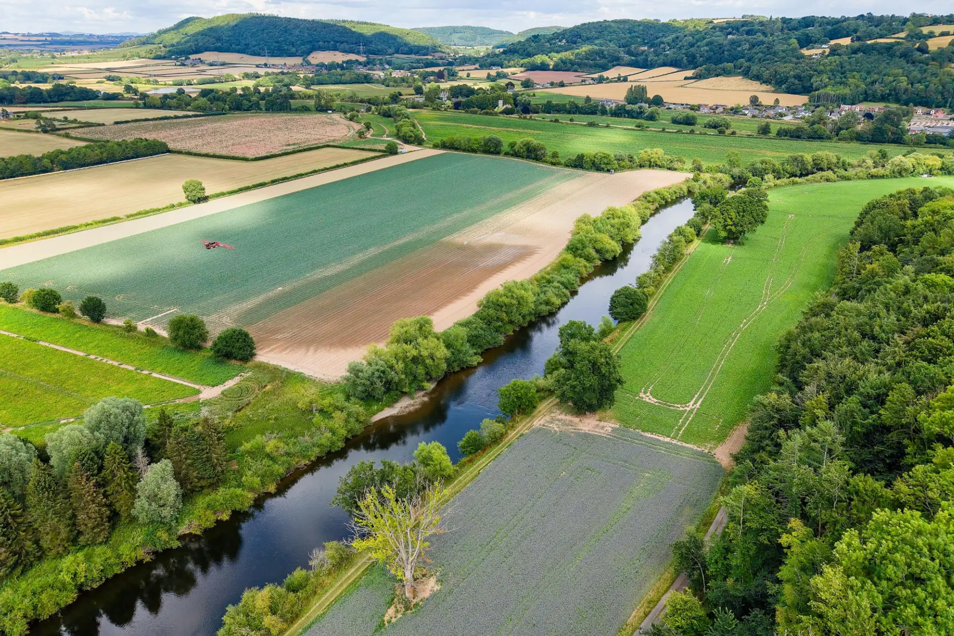 River bordered by agricultural fields, trees and rural landscapes